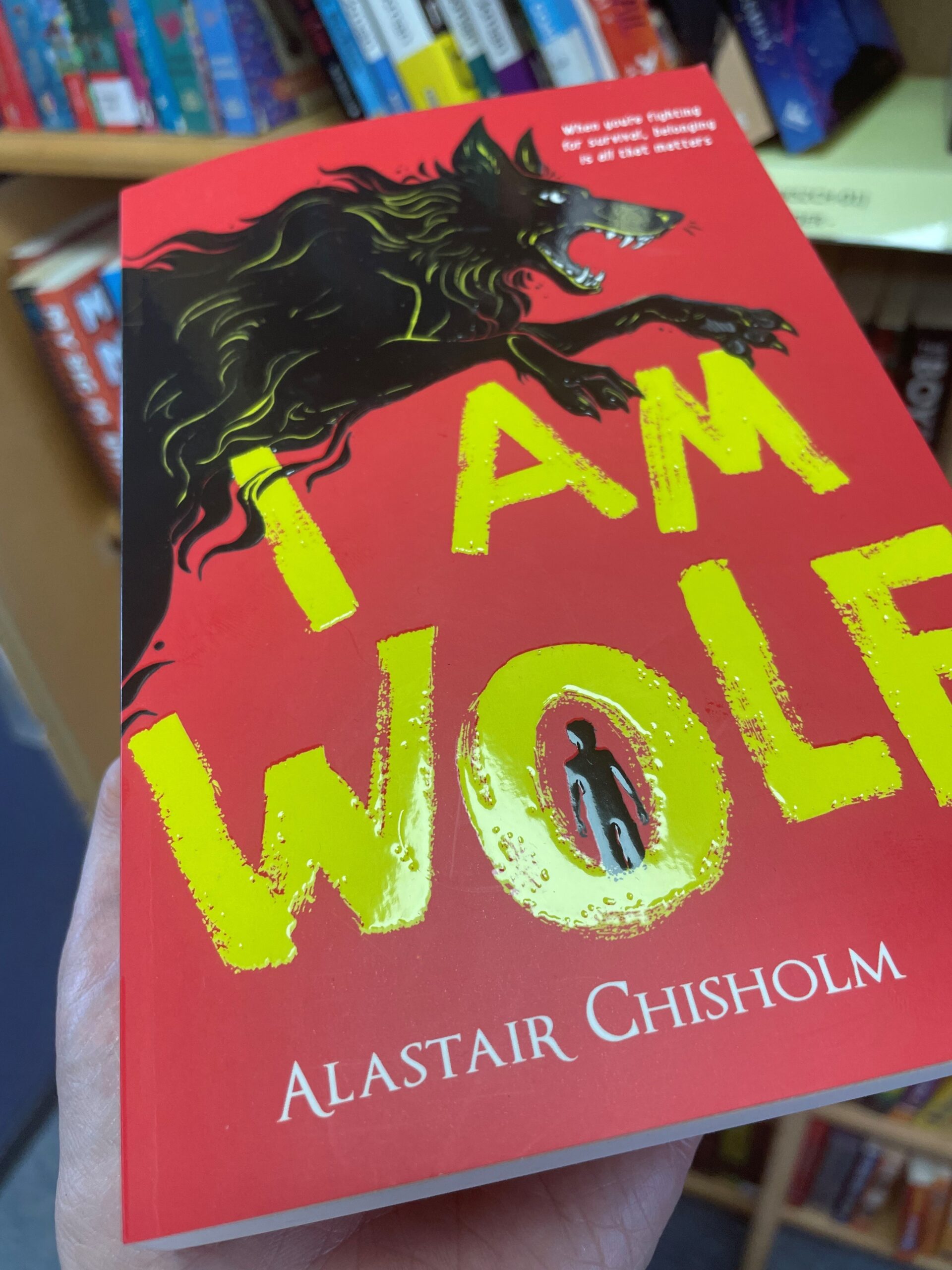 Photo of I am Wolf held in front of a bookshelf of books